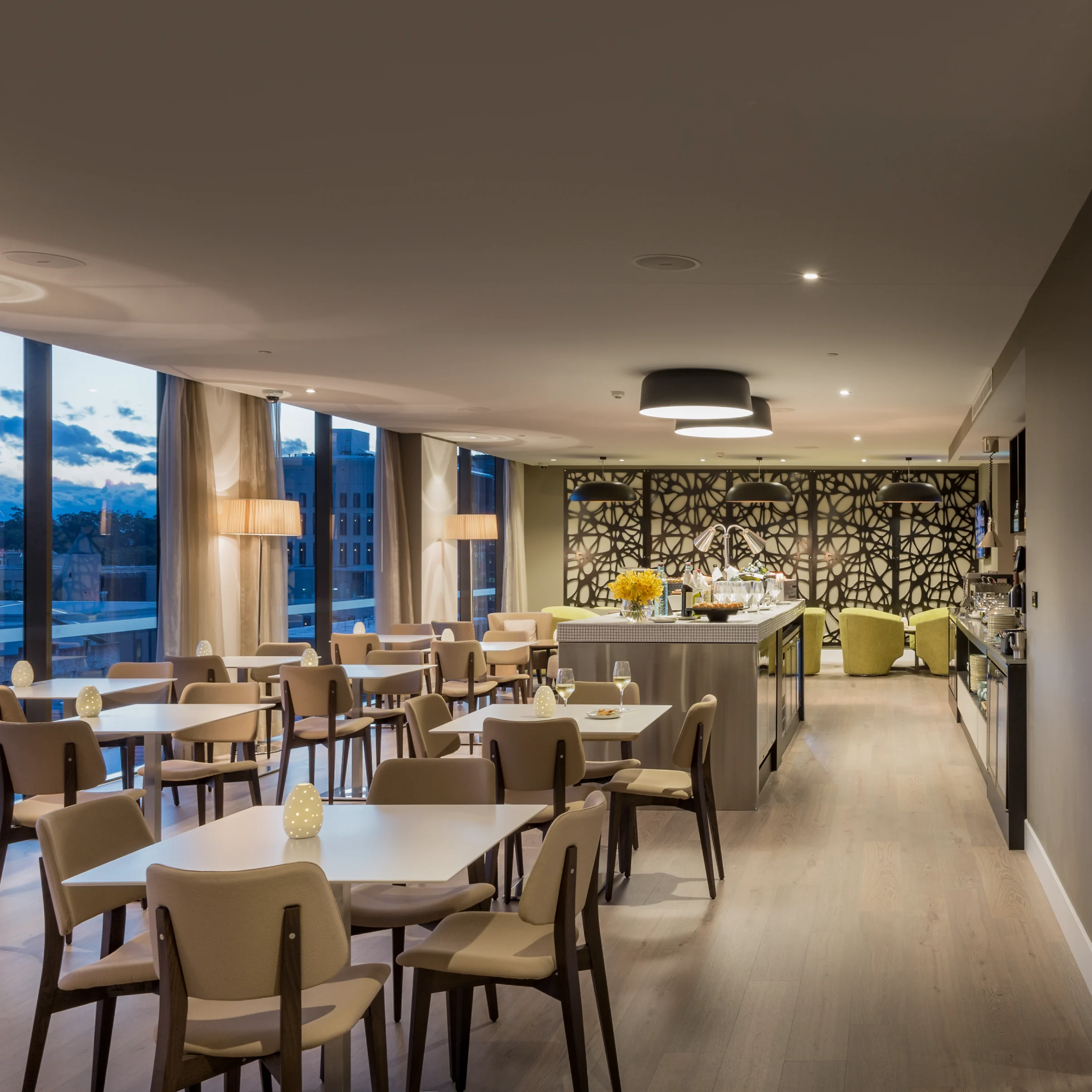 Modern hotel restaurant with wood tables, upholstered chairs, city views, and buffet; adjoining conference room creates a warm, polished atmosphere.