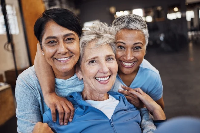 Three smiling elderly women embracing