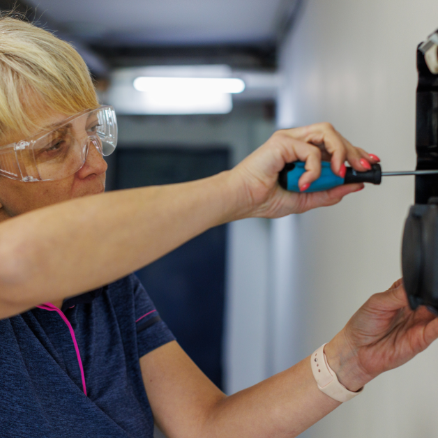 Woman in protective eyewear and holding a screwdriver