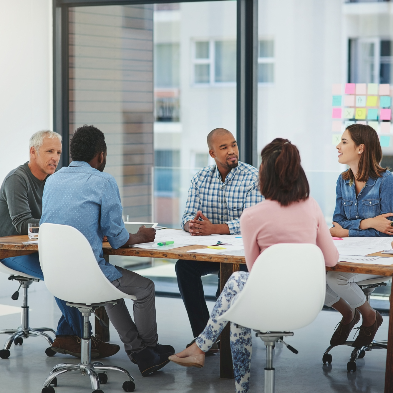Men and women sitting around meeting table in white chairs