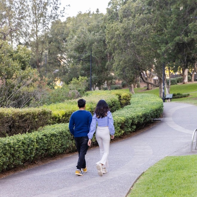 Man and woman walking on footpath in park.