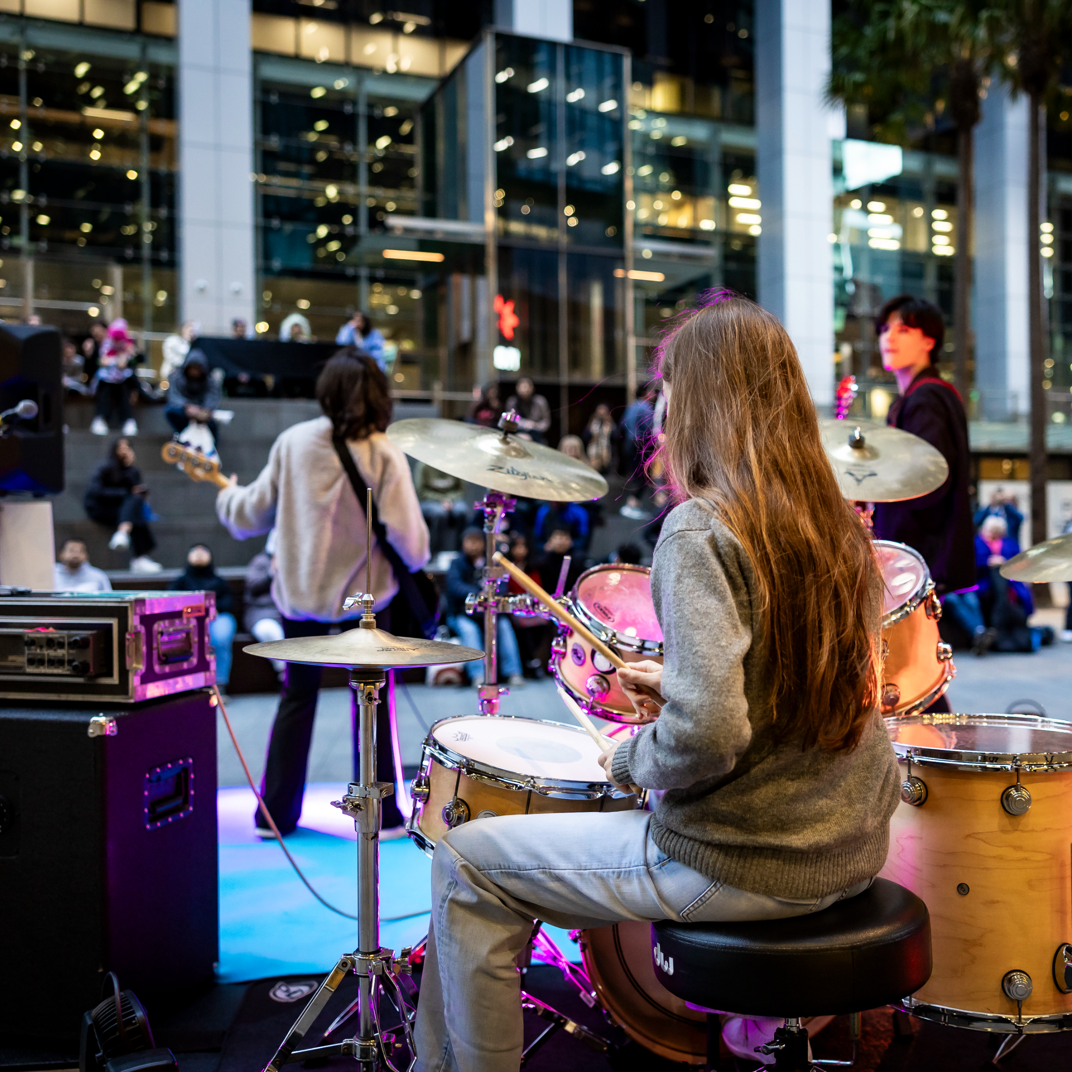 Elegantly set dining table with glasses and napkins is surrounded by plush chairs, framed by large windows offering a modern cityscape view.