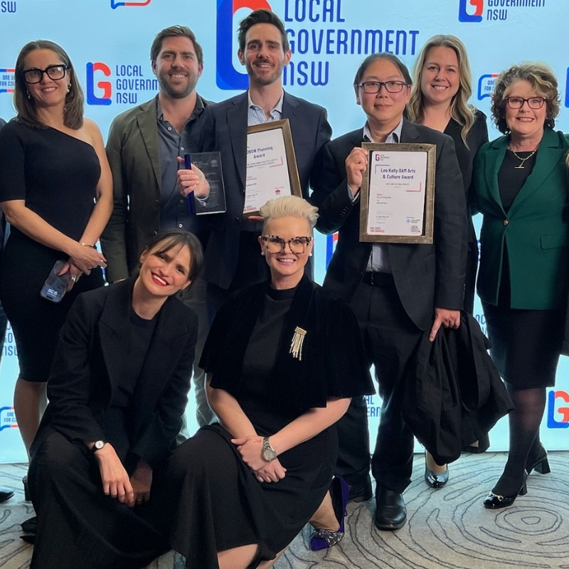 Smiling men and women holding two awards in frames from Local Government NSW