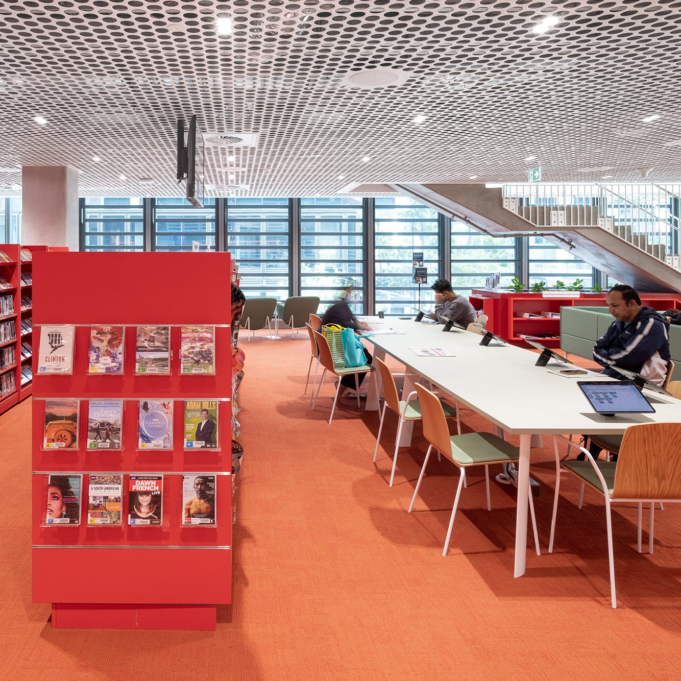 three people sitting at a desk inside a library