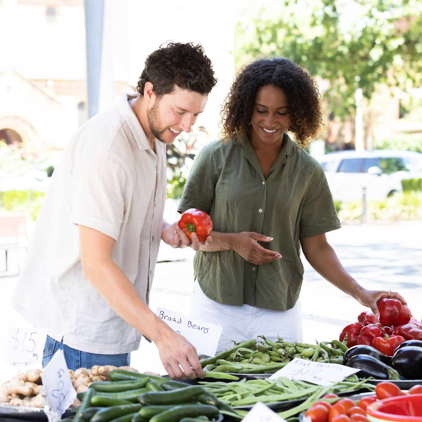 A man and a woman smiling and choosing vegetables