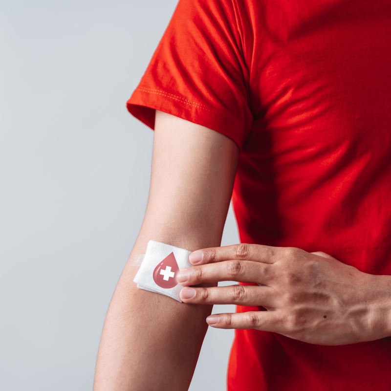 A person showing a patch on their elbow to promote giving blood