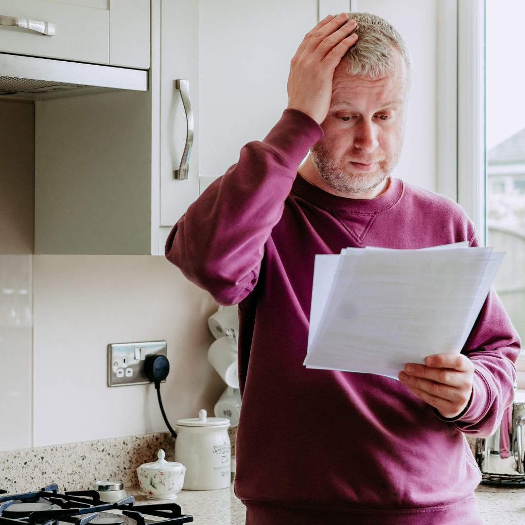 A man holding his head looking at papers