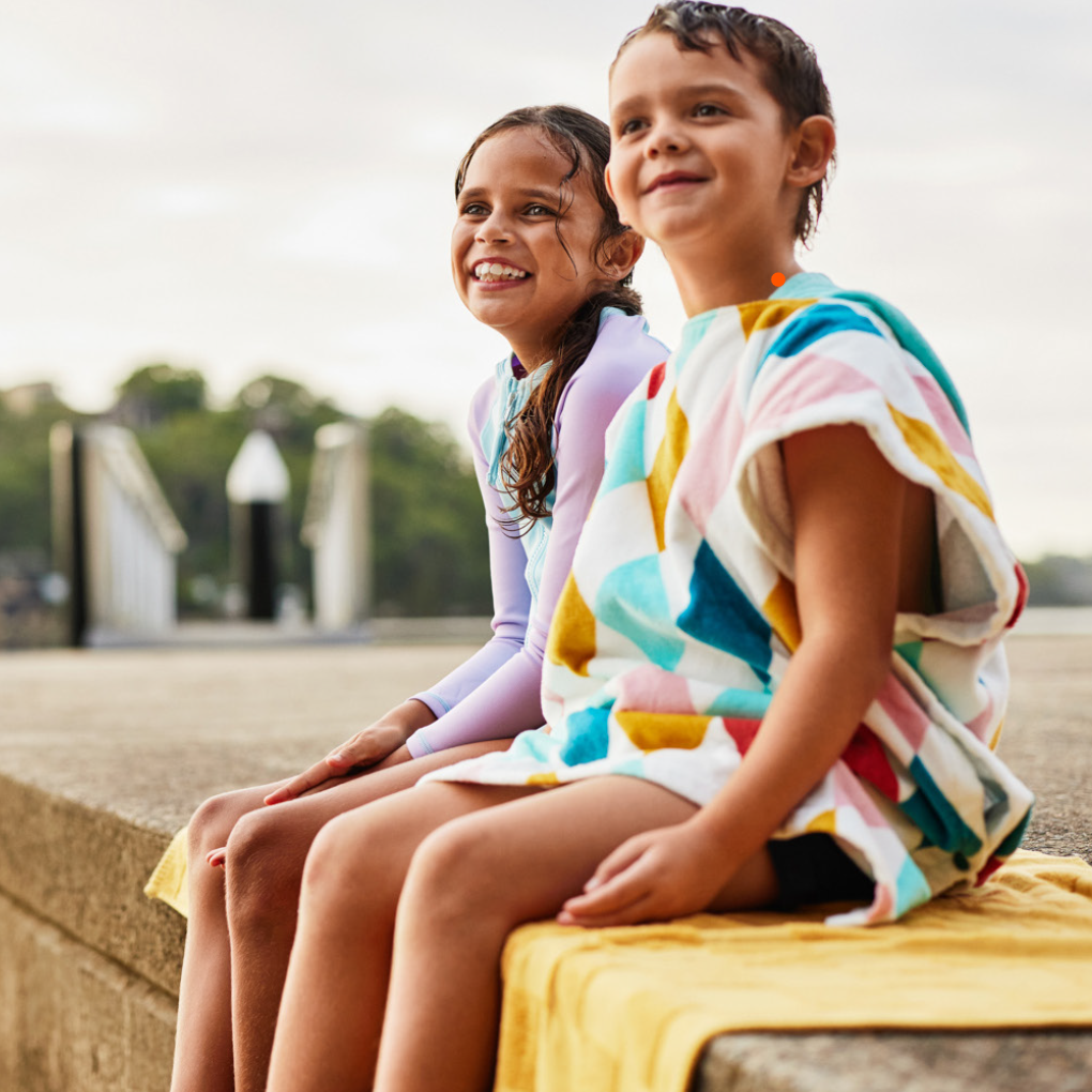 A boy and girl in their swimsuits sitting on a dock